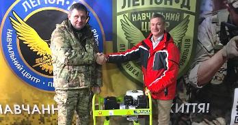 SIS alumnus Andrew Kinsel (right) donates a generator to a member of the Ukrainian armed forces.