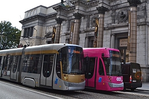 A silver and a pink tram on the streets of the city