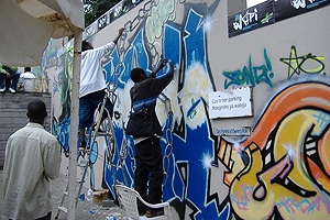 Men spray painting artistic graffiti on city walls.