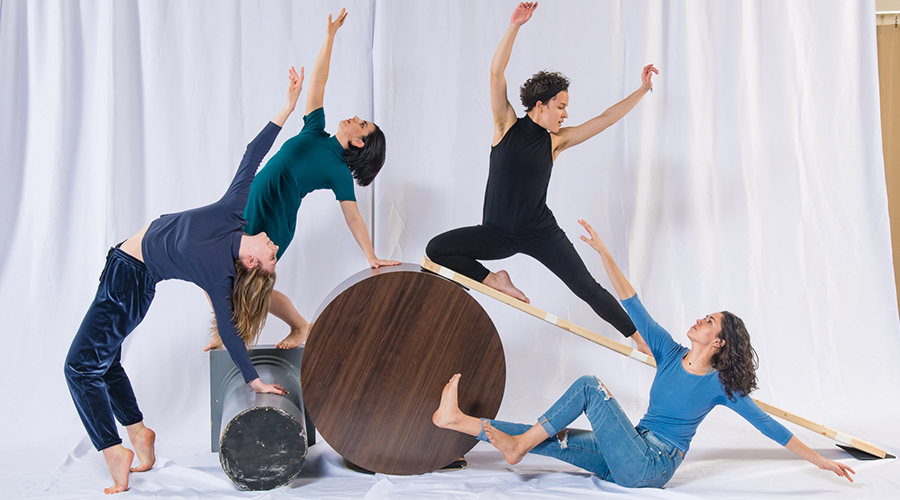 Four people pose atop tables and boards