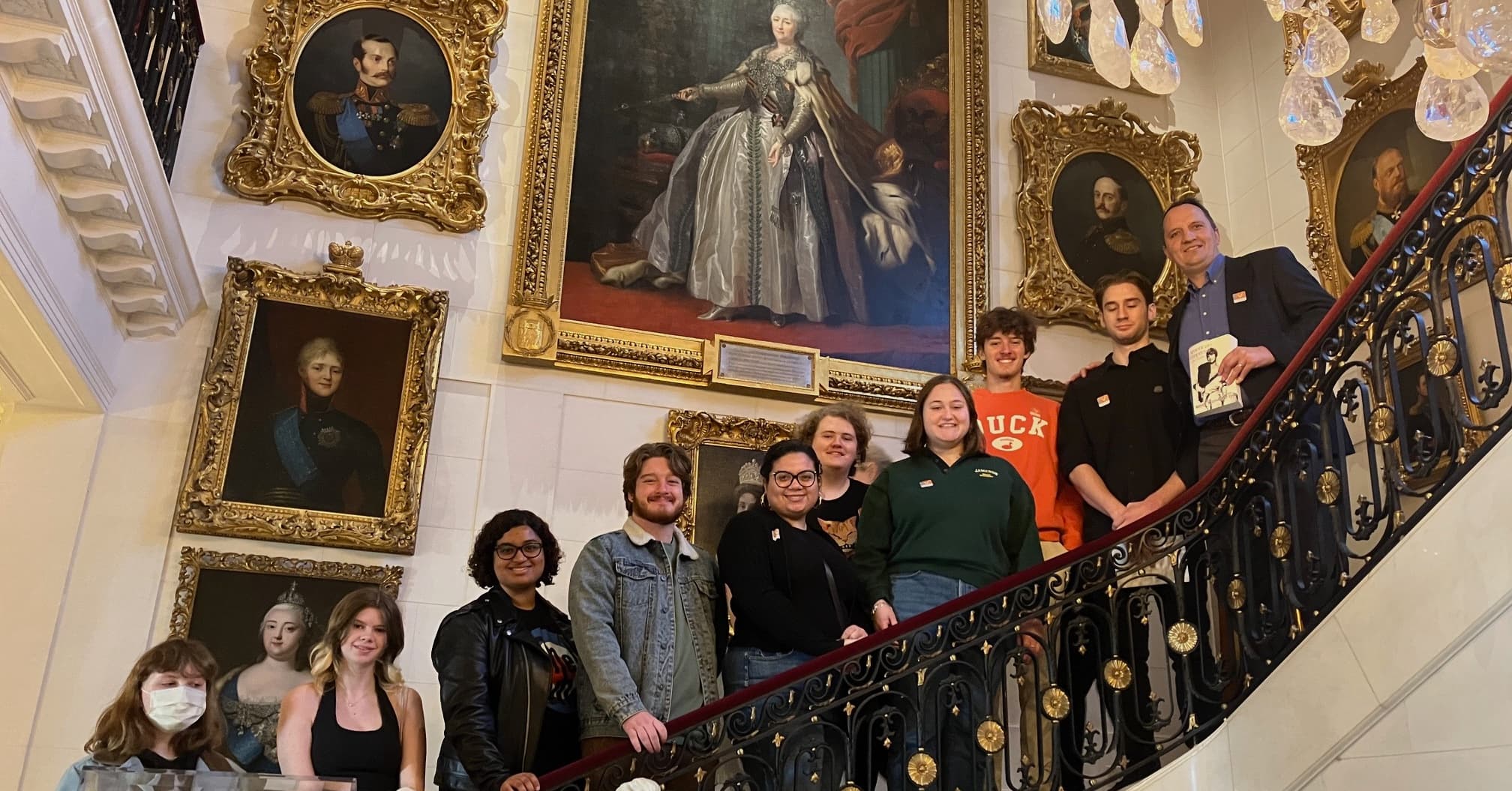 Students on the Hillwood House Grand Staircase with paintings of Russian Tsars and nobility on the walls.
