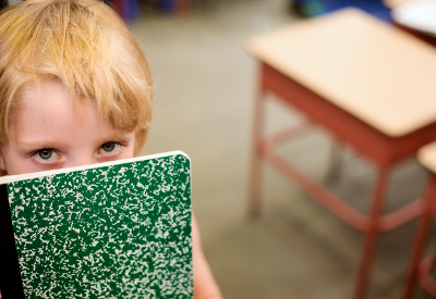 A child hides behind a composition book.