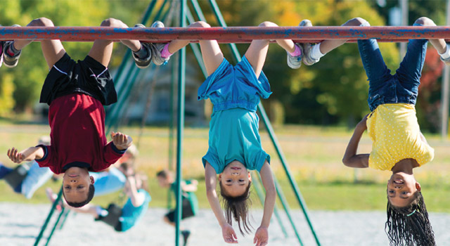 Kids hanging upside down on playground.