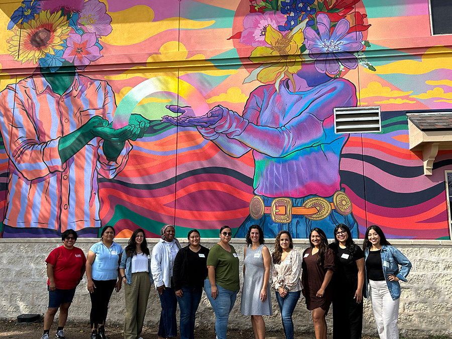 Community advisory board posing in front of mural