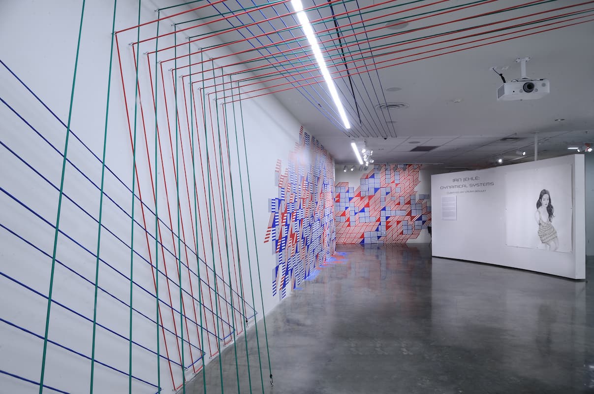 Installation view of multimedia exhibition with tape, portraiture, and bungee cords