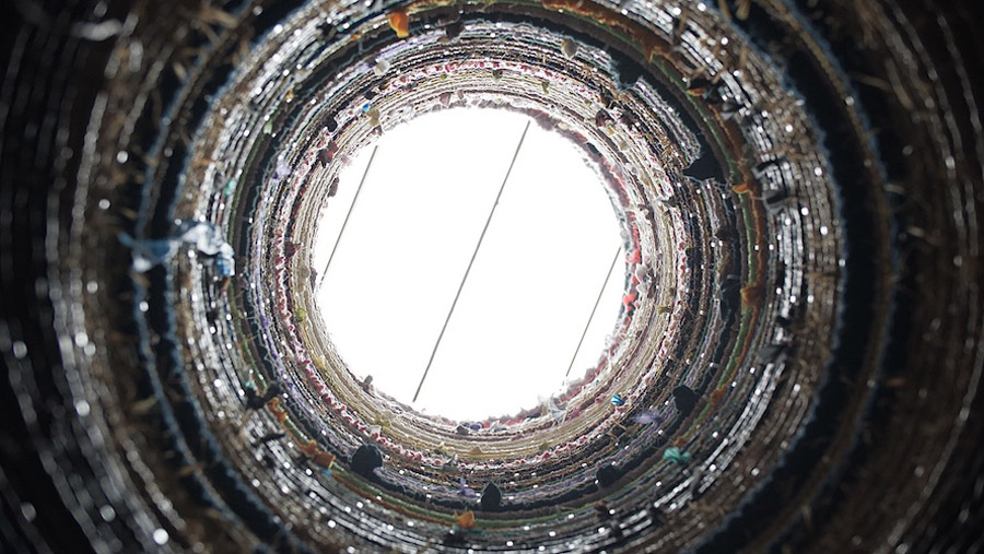 Hyunsuk Erickson, Auspicious Energy Circle, 2021, PVC Pipe, Fabric, Yaen, Package String, Zip-tie, 550 cord, Hay. Looking through a tunnel-like sculpture