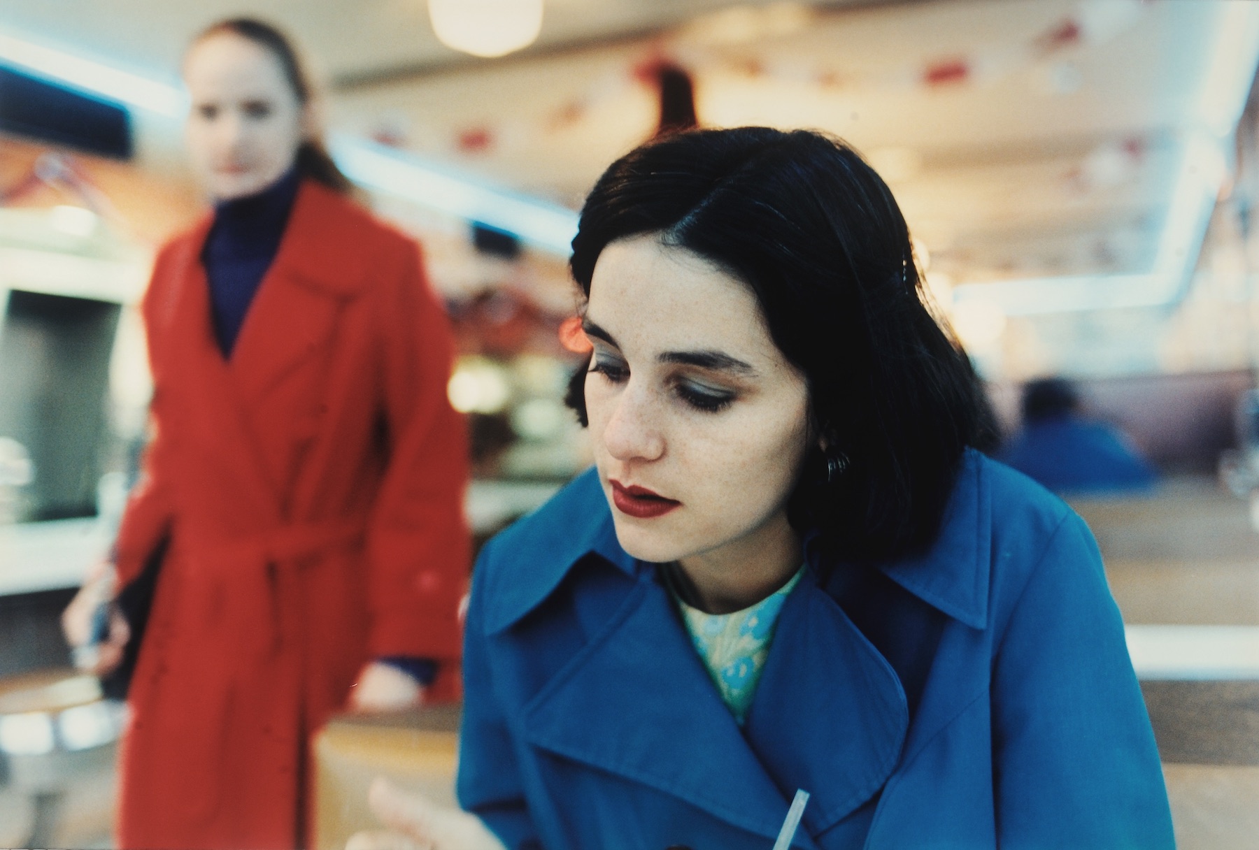 Two women, in blue and red coats