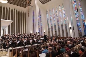 An orchestra and chorus perform in front of an audience at the National Presbyterian Church