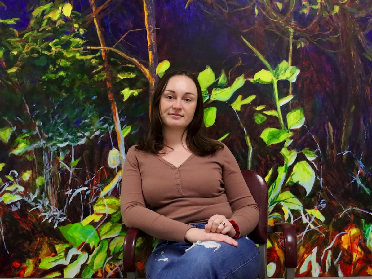 Lindsay Mueller seated in front of painted foliage