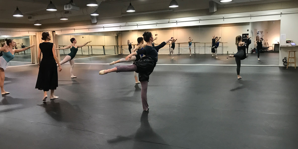 Students stand in arabesque in the dance studio