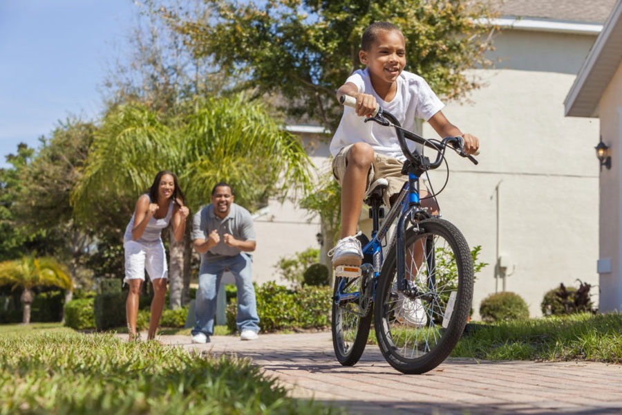 Child zooms past on bike as parents cheer