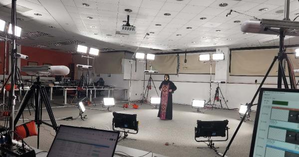 A woman dressed in traditional Emirati clothing stands at the center of a volumetric capture studio stage