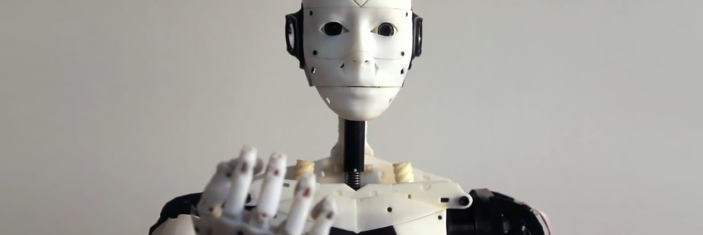 A closeup of a robot's face with an outstretched hand.