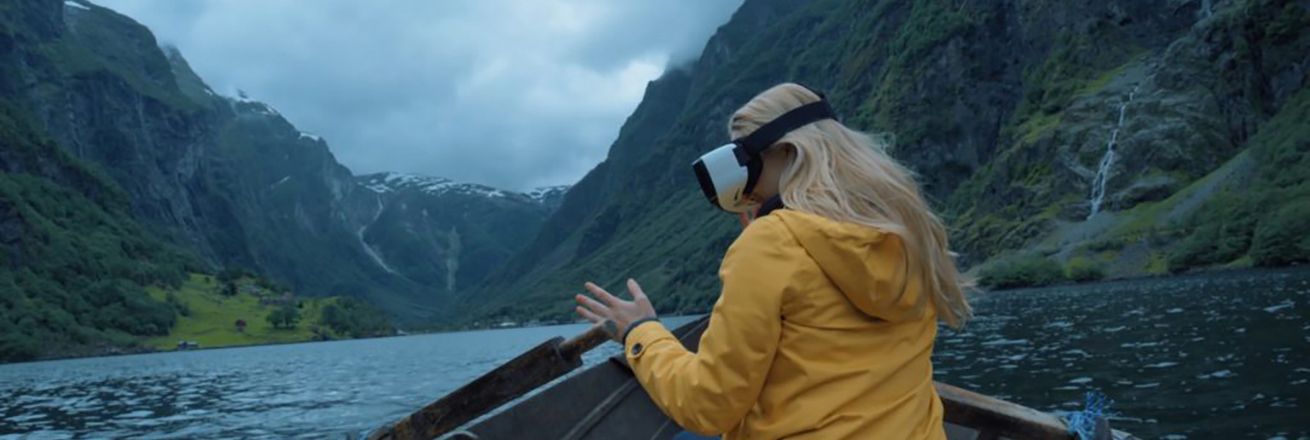 A woman in a VR headseat overlooking the water on a boat.