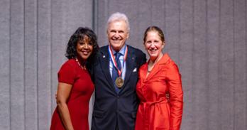 (left to right) AU Board of Trustees chair Gina Adams, Ambassador Stuart Bernstein, and AU President Sylvia M. Burwell stand together onstage at the 2023 President's Circle Celebration