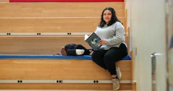 Rosy Chavez-Martinez sits reading on the steps in the School of International Service atrium at American University.