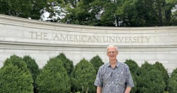 Gary Wright standing in front of the American University gate on campus.