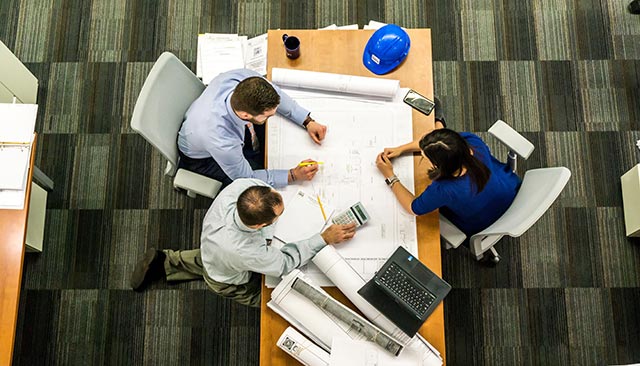 People discussing architectural drawings at a table