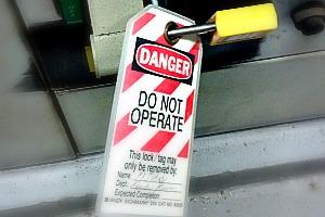 A tag locked onto some equipment with the words, "Danger, Do Not Operate. This lock may only be removed by" and then a faded out signature