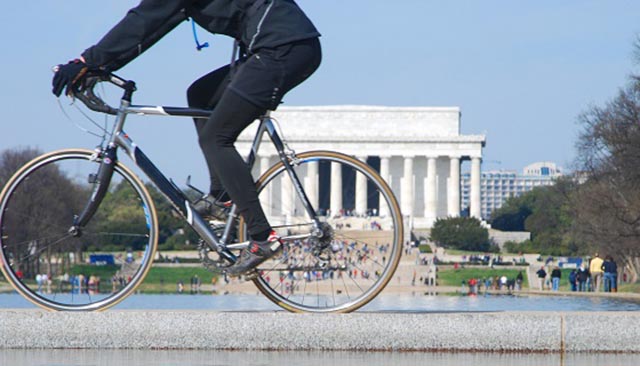 A cyclist rides past the Lincoln Memorial