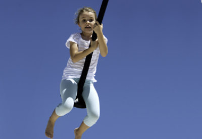 A scared child swinging on a rope.