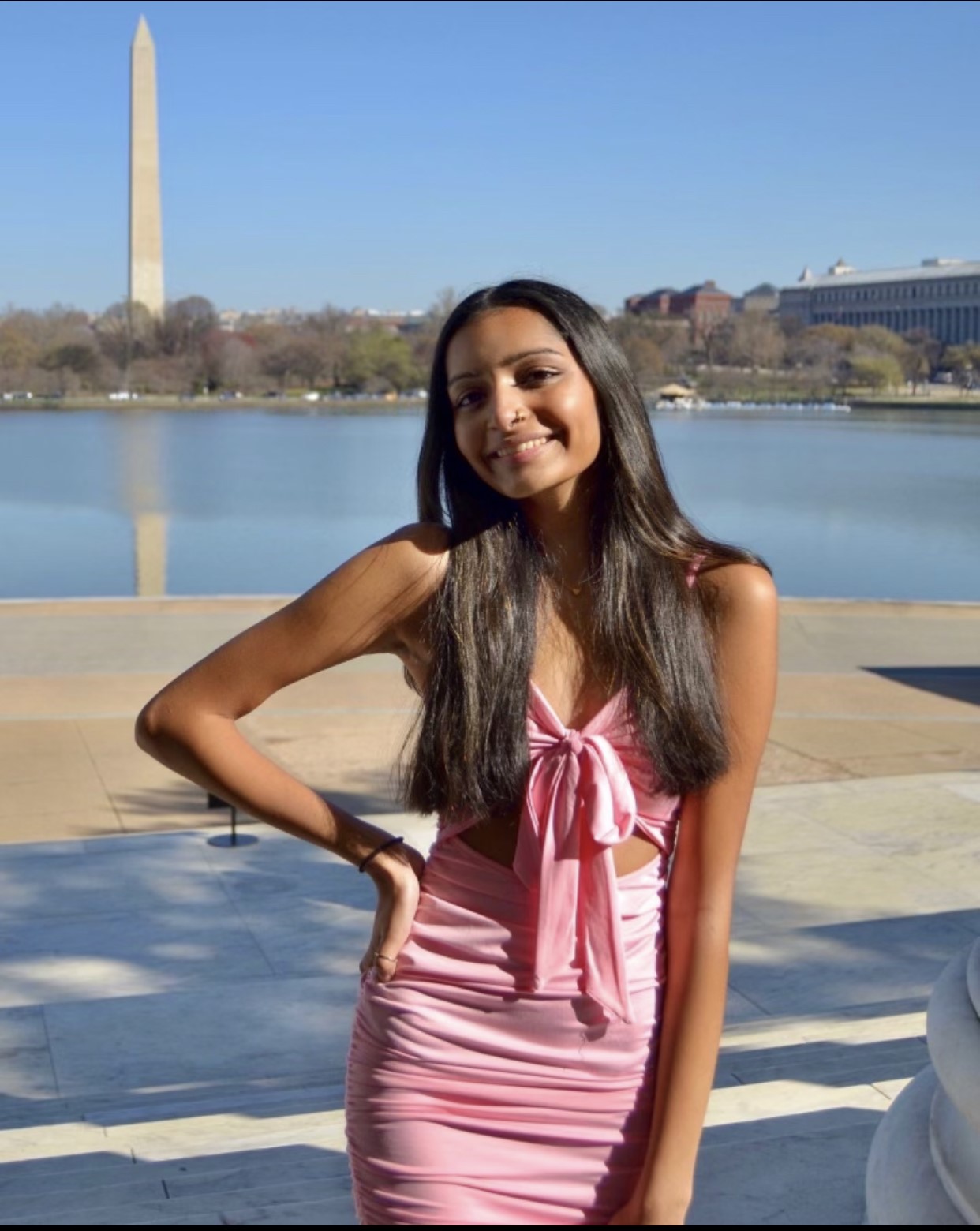 a photo of Diya in a pink dress posing in front of the Washington Monument and the reflecting pool