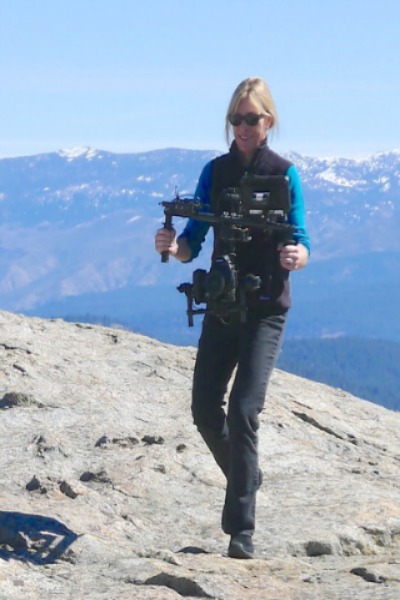 Professor Maggie Stogner filming on top of a mountain