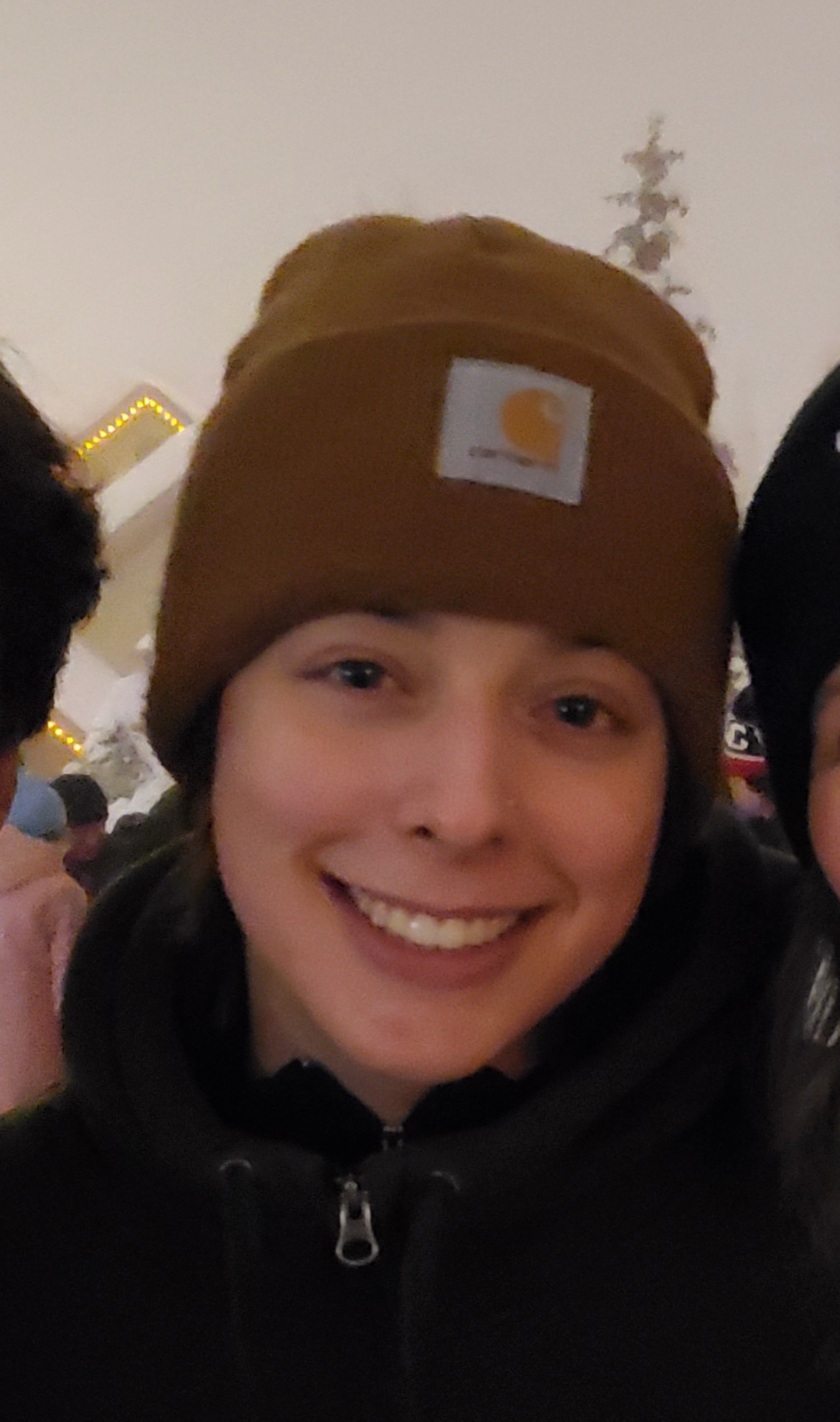 A close up photo of devon wearing a black hoodie and a brown beanie.