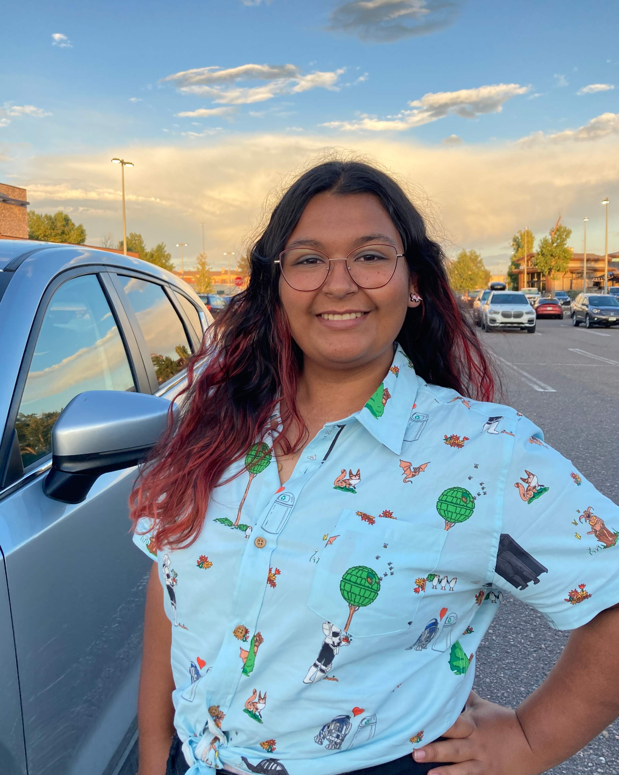 Zophia wearing a patterned shirt standing with a hand on her hip