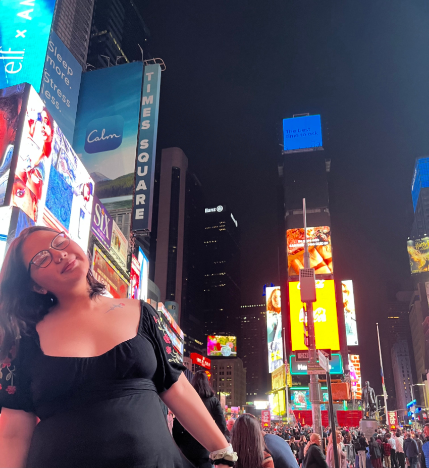 Maddy in a black dress posing in Times Squre New York