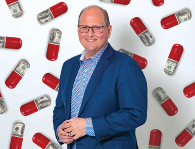 Kevin Hagan stands against a backdrop of pill capsules that are half red, half made of US currency bills