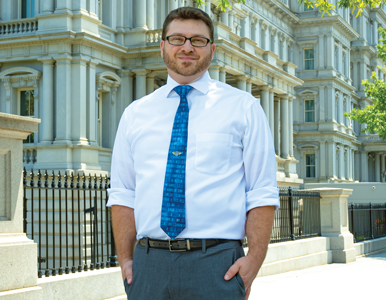 Jay Teitelbaum wears a white button down and blue tie while standing in front of the Eisenhower Executive Office Building