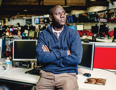 Derek Karikari sits on his desk at the AP newsroom in London
