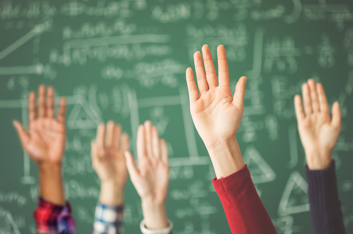 kids raising their hands in front of a chalkboard