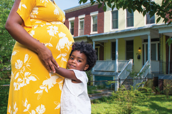 pregnant Black woman hugging a small child