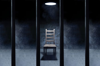 an empty interrogation chair in a prison cell
