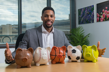 Romone Penny inserts money into a piggy bank shaped like a football