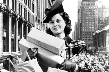 Black and white photo of a woman holding several gift boxes