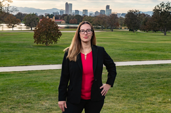 Christine Hernandez stands in a park with downtown Denver in the background