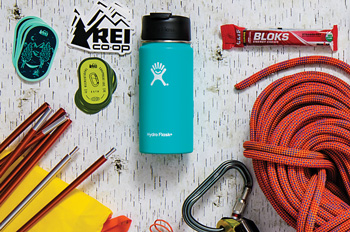 REI stickers, a tent, a coffee thermos, energy chews, a belaying device, climbing rope, car keys, a fleece jacket, a laptop, a smart phone, trail running shoes, bike lube, and a bike helmet