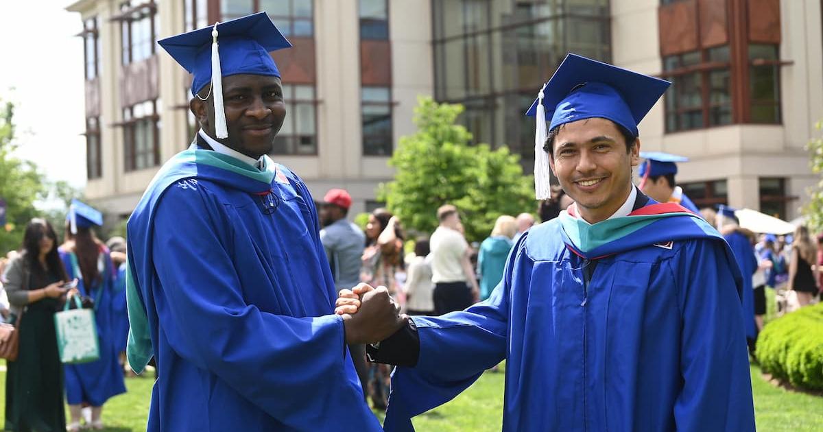 Two SIS graduates shake hands outside of the SIS Building. Photo by Jeff Watts.