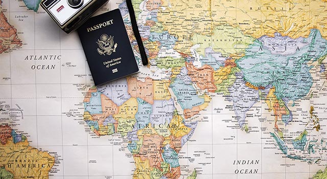 old film camera and US passport lay on top of a world map