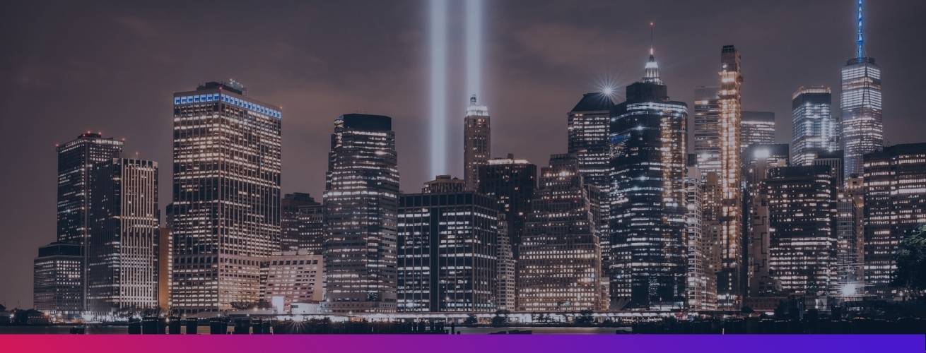 New York City skyline at night with two beams of light in air representing the World Trade Center buildings