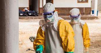 Two people in Ebola personal protective gear in a dry setting