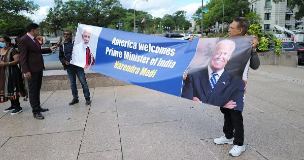 Two men hold a sign welcoming Indian Prime Minister Narendra Modi to the United States