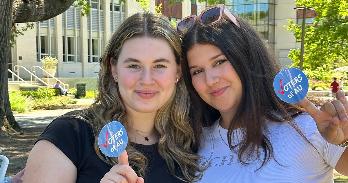 SIS student Emma Baumgarten and SPA student Alyssa Levin pose with Voters of AU stickers