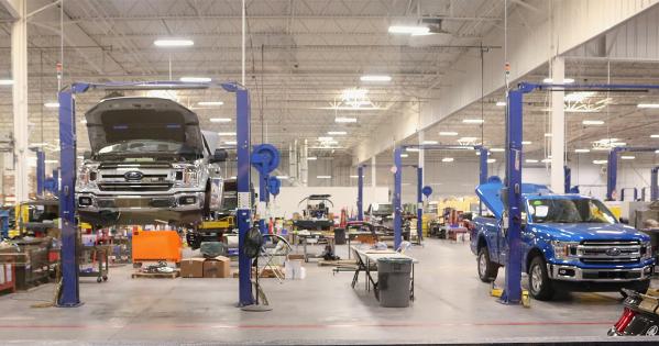 two Ford automobiles up on mechanical jacks in an automative manufacturing warehouse