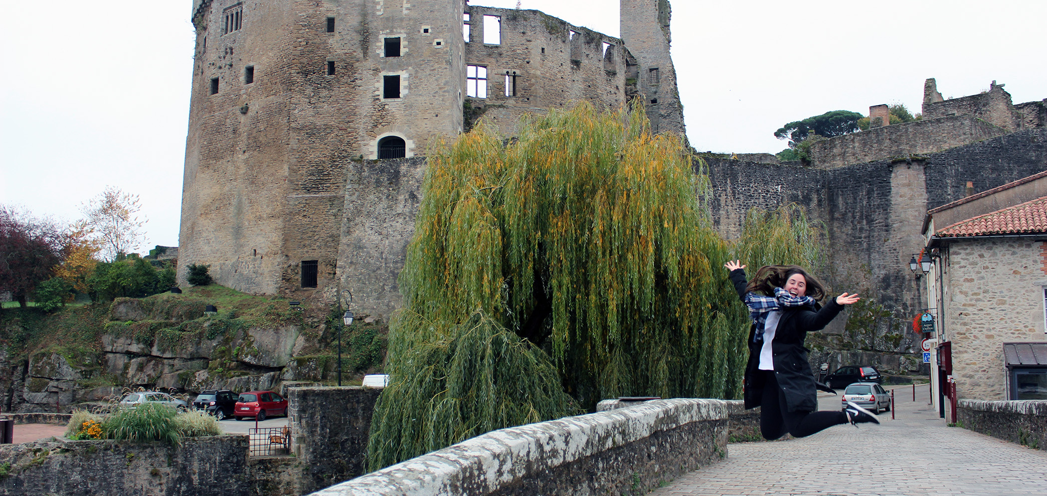 A student jumps for joy outside of a castle in France.