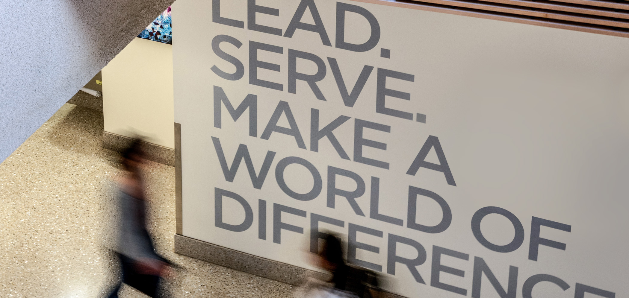 Students walk past a sign that says, 