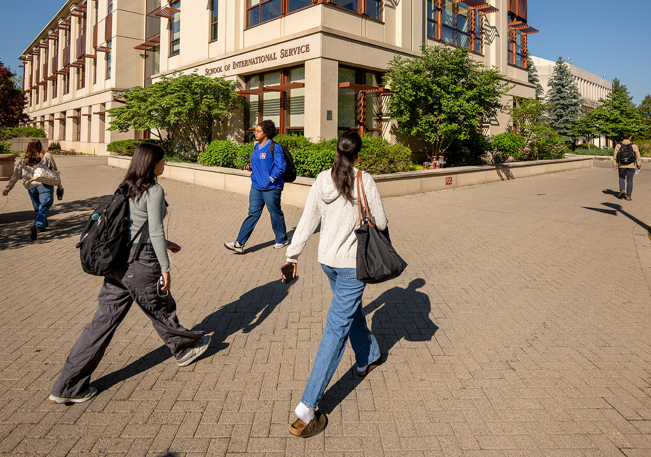 Busy students walk past the SIS building on a sunny day.